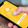 A person holding a smartphone displaying the Bumble app's login screen. A person holding a smartphone displaying the Bumble app's login screen.