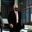 Postmaster General Louis DeJoy arriving at a government building, accompanied by two individuals, while wearing a mask. Postmaster General Louis DeJoy arriving at a government building, accompanied by two individuals, while wearing a mask.