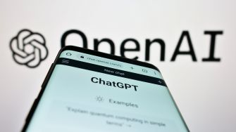 A smartphone displaying the ChatGPT interface in front of an OpenAI logo.