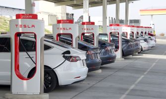 A row of Tesla vehicles charging at a Tesla Supercharger station.