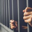 A close-up of hands gripping jail cell bars, symbolizing confinement and lack of support. A close-up of hands gripping jail cell bars, symbolizing confinement and lack of support.