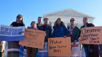 A group of people holding signs in support of the Indian Child Welfare Act (ICWA) in front of the U.S. Supreme Court building.
