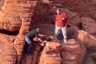 Two men on a rock formation in the Lake Mead National Recreation Area, allegedly involved in toppling ancient red rock formations.