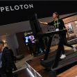Peloton treadmill on display at a fitness expo with a woman demonstrating its use. Peloton treadmill on display at a fitness expo with a woman demonstrating its use.