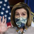 A woman wearing a mask gestures while speaking at a podium with flags in the background. A woman wearing a mask gestures while speaking at a podium with flags in the background.