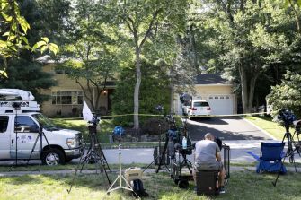 A scene outside a home with news cameras set up, following a violent incident involving a judge's family.