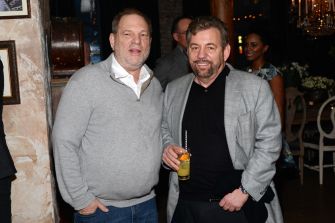 Image of Harvey Weinstein and James Dolan at an event, both in casual attire, standing together with drinks.