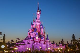 Disneyland's iconic castle illuminated at dusk.