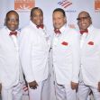 Four members of the Four Tops, dressed in formal attire, posing together at an event. Four members of the Four Tops, dressed in formal attire, posing together at an event.