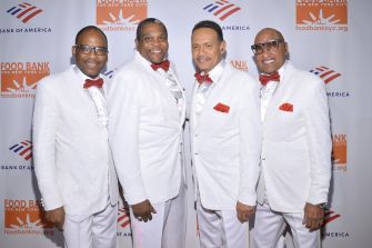 Four members of the Four Tops, dressed in formal attire, posing together at an event.