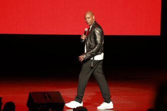 Dave Chappelle performing on stage during a live comedy show.