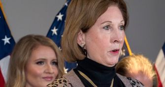 Image of Sidney Powell speaking at a press conference, with flags in the background.