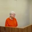 76-year-old woman in an orange jumpsuit appearing in a courtroom. 76-year-old woman in an orange jumpsuit appearing in a courtroom.