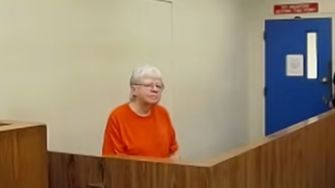 76-year-old woman in an orange jumpsuit appearing in a courtroom.