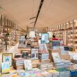 A modern bookstore interior filled with rows of books on shelves and a display of titles in the foreground. A modern bookstore interior filled with rows of books on shelves and a display of titles in the foreground.