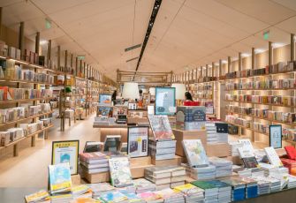 A modern bookstore interior filled with rows of books on shelves and a display of titles in the foreground.