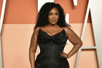 Lizzo posing in a black fashion outfit at a public event.