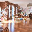 A brightly lit daycare room with wooden floors, child-sized furniture, educational posters on the walls, and scattered toys on the floor. A brightly lit daycare room with wooden floors, child-sized furniture, educational posters on the walls, and scattered toys on the floor.