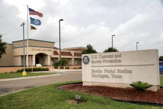 Sign for U.S. Customs and Border Protection Border Patrol Station in Harlingen, Texas, with flags in the background.