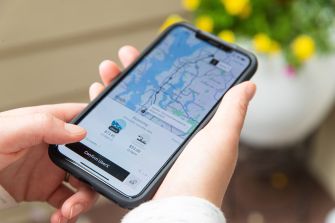 A person holds a smartphone displaying the Uber app's map and ride options.