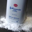 Container of Johnson's Baby Powder with powder spilled out on a surface. Container of Johnson's Baby Powder with powder spilled out on a surface.