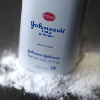 Container of Johnson's Baby Powder with powder spilled out on a surface.