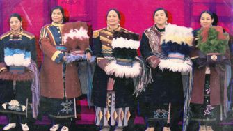 Costume designers wearing traditional attire, standing together, showcasing cultural garments.