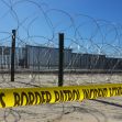 A view of the U.S.-Mexico border featuring barbed wire and caution tape, highlighting border security measures. A view of the U.S.-Mexico border featuring barbed wire and caution tape, highlighting border security measures.