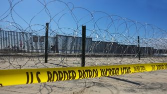 A view of the U.S.-Mexico border featuring barbed wire and caution tape, highlighting border security measures.