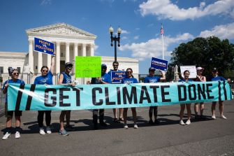 Protesters holding a large banner reading "GET CLIMATE DONE" in front of the Supreme Court building, advocating for climate action.
