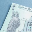 Image of a U.S. check featuring the Statue of Liberty alongside several $100 bills. Image of a U.S. check featuring the Statue of Liberty alongside several $100 bills.