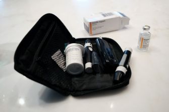 A kit containing insulin supplies, including vials and pens, on a surface with a box labeled 'Insulin Aspart'.