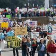 A large group of protesters marching with various signs advocating for immigrant rights and justice. A large group of protesters marching with various signs advocating for immigrant rights and justice.