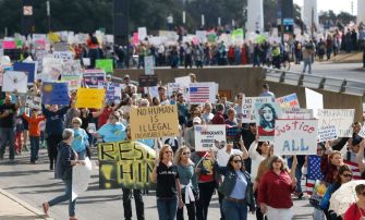 A large group of protesters marching with various signs advocating for immigrant rights and justice.