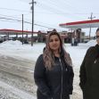 Two women standing outside in a snowy area near a gas station. Two women standing outside in a snowy area near a gas station.