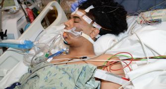 Inmate Brian Ortiz receiving medical treatment after a brutal assault, surrounded by medical equipment in a hospital setting.