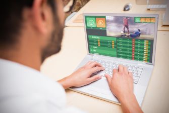 A person placing an online sports bet using a laptop.