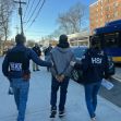 Arrest of New York City Housing Authority workers amid a corruption scandal, with law enforcement escorting a handcuffed individual. Arrest of New York City Housing Authority workers amid a corruption scandal, with law enforcement escorting a handcuffed individual.
