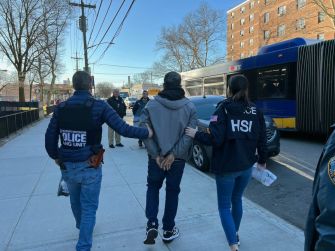Arrest of New York City Housing Authority workers amid a corruption scandal, with law enforcement escorting a handcuffed individual.