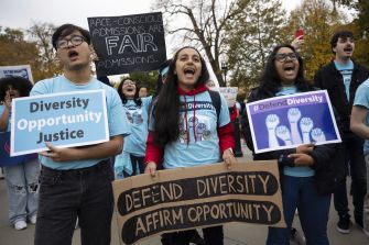 A group of diverse protesters holding signs in support of affirmative action and diversity in college admissions.