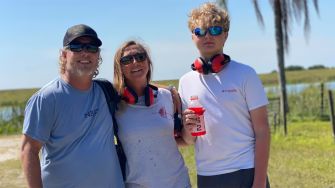 A family posing together outdoors, smiling, with a scenic background.