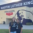 Two female athletes from Martin Luther King High School standing in front of the school building, wearing t-shirts that promote girls' sports. Two female athletes from Martin Luther King High School standing in front of the school building, wearing t-shirts that promote girls' sports.