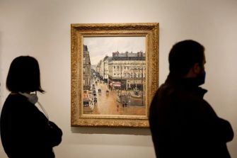 A painting by Camille Pissarro displayed at an art museum, with two visitors observing it.
