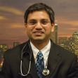 A portrait of a doctor wearing a suit and stethoscope, taken in front of a city skyline background. A portrait of a doctor wearing a suit and stethoscope, taken in front of a city skyline background.
