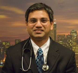 A portrait of a doctor wearing a suit and stethoscope, taken in front of a city skyline background.