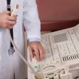 A medical professional adjusting an ultrasound machine in a clinical setting. A medical professional adjusting an ultrasound machine in a clinical setting.
