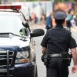 A police officer walking away from a police vehicle on a city street. A police officer walking away from a police vehicle on a city street.