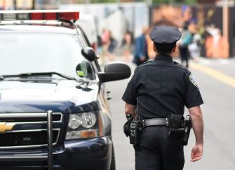 A police officer walking away from a police vehicle on a city street.