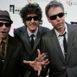 Three men in suits with sunglasses and hats pose together at an event. Three men in suits with sunglasses and hats pose together at an event.