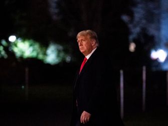 Former President Trump walking outside at night.